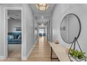 Bright hallway with wood floors, elegant lighting, and a stylish round mirror on a console table at 10144 E Thistle Ave, Mesa, AZ 85212