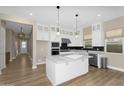 Modern kitchen with white cabinets, a center island, stainless steel appliances, and stylish backsplash at 10144 E Thistle Ave, Mesa, AZ 85212