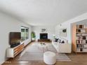 Bright living room featuring a modern fireplace, striped rug, light wood floors and large windows at 1810 W Kiowa Cir, Mesa, AZ 85202