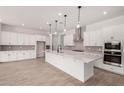 Spacious kitchen showcasing white cabinets, a quartz island, stainless steel appliances, and tile backsplash at 20273 W Monterey Way, Buckeye, AZ 85396