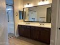 Elegant bathroom with double vanity, dark wood cabinets, a large mirror, and a glass-enclosed shower at 23102 E Raven Dr, Queen Creek, AZ 85142