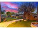 Landscaped backyard with a stone walkway, lush lawn, archway, and vibrant sunset at 30600 N Pima Rd # 49, Scottsdale, AZ 85266