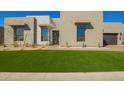 Modern home with neutral stucco, black framed windows, desert landscaping, and inviting green lawn at 5724 E Moura Dr, Cave Creek, AZ 85331