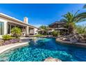 Sparkling pool surrounded by lush landscaping, a covered seating area, and mature palm trees at 11336 N 117Th Way, Scottsdale, AZ 85259