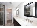 Bathroom featuring dual sinks, quartz countertops, dark cabinets and a walk-in closet at 1966 E Pebble Beach Dr, Tempe, AZ 85282