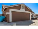 Side view of the two car garage with brown door and desert landscaping, ready to park your cars! at 19801 N 6Th Pl, Phoenix, AZ 85024