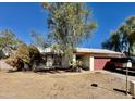 A single-story home features a two-car garage, desert landscaping, and mature trees under a bright blue sky at 5040 N 69Th Dr, Glendale, AZ 85303