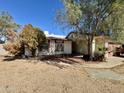 A single-story home features desert landscaping and mature trees under a bright blue sky at 5040 N 69Th Dr, Glendale, AZ 85303