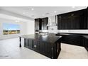 Modern kitchen with dark cabinets, stainless steel appliances, an island, and a view to the backyard at 5779 N 207Th Ave, Buckeye, AZ 85396