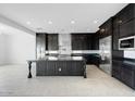 Bright kitchen with dark cabinets, a large island and stainless steel appliances in an open layout at 5779 N 207Th Ave, Buckeye, AZ 85396