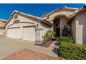 Inviting home exterior featuring a three-car garage and attractive desert landscaping at 654 W Natal Cir, Mesa, AZ 85210