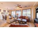 Bright living room with leather sofa, light-colored armchairs, fan, and large windows overlooking the landscape at 13068 W Mine Trl, Peoria, AZ 85383