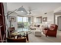 Bright living room with a ceiling fan, glass table, comfortable seating, and access to an outdoor balcony at 15802 N 71St St # 311, Scottsdale, AZ 85254