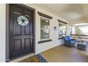 Inviting front porch featuring a dark entry door, comfortable seating, and stylish decor at 20897 W Edith Way, Buckeye, AZ 85396