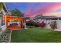 Beautiful backyard featuring a covered patio with string lights, artificial turf, and lush landscaping at 2321 N Glenview --, Mesa, AZ 85213