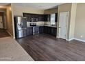 Modern kitchen with stainless steel appliances, dark cabinets, granite countertops, and wood floors at 36905 W Mattino Ln, Maricopa, AZ 85138