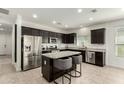 Modern kitchen with granite countertops, stainless steel appliances, a central island and dark wood cabinetry at 37783 W San Sisto Ave, Maricopa, AZ 85138