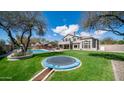 Expansive backyard featuring lush green grass, a trampoline, and a sparkling pool at 6929 E Trailridge Cir, Mesa, AZ 85207