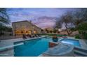 Twilight view of a backyard with string lights, pool, and a relaxing spa at 6929 E Trailridge Cir, Mesa, AZ 85207