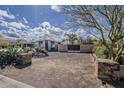 A unique desert landscape home with a private gated driveway, mature trees, and tasteful stone accents at 7131 E Cholla St, Scottsdale, AZ 85254