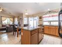 Open kitchen with an island, granite countertops, oak cabinets, and adjacent dining area with tile floors at 85 W Grey Stone St, San Tan Valley, AZ 85143