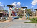 Community Adventure Playground, featuring colorful equipment, surrounded by lush landscaping and blue skies, offers outdoor fun for families at 8559 W Trenton Ct, Florence, AZ 85132