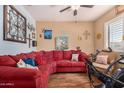 Comfortable living room featuring a red sectional sofa, ceiling fan, and bright natural light at 1708 N Burbank Ct, Chandler, AZ 85225