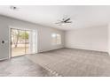 Bright living room featuring carpet, neutral walls, ceiling fan, and sliding glass door to backyard at 2023 S 106Th Ave, Tolleson, AZ 85353