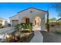 Front exterior featuring an arched entryway, desert landscaping, and a two-car garage at 20701 W Minnezona Ave, Buckeye, AZ 85396