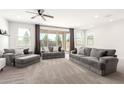 Spacious living room featuring neutral carpeting, large windows, and stylish gray sofas at 21295 E Estrella Rd, Queen Creek, AZ 85142