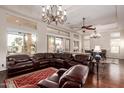 Expansive living room with dark wood floors, elegant chandeliers, and a comfortable leather sofa at 3234 N 163Rd Dr, Goodyear, AZ 85395