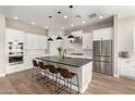 Modern kitchen featuring white cabinetry, stainless steel appliances, a dark island countertop, and wood-style flooring at 5700 N 202Nd Ln, Litchfield Park, AZ 85340