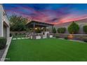 Well-manicured backyard featuring a covered patio with an outdoor fireplace and lush, green grass at 610 W Tonto Dr, Chandler, AZ 85248