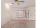 Well-lit living room showcasing a large bay window with shutters and a modern ceiling fan at 9526 W Menadota Dr, Peoria, AZ 85382