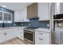 Well-designed kitchen features white cabinets, stainless steel appliances, and a blue tile backsplash at 1530 W Glenrosa Ave, Phoenix, AZ 85015