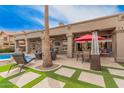 A covered patio offers an outdoor dining and lounge area with views of the pool and manicured lawn at 1668 E Saltsage Dr, Phoenix, AZ 85048