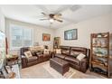 Cozy living room with plush leather seating, ceiling fan, and natural light, creating a comfortable space to unwind at 18438 W Brookwood Dr, Goodyear, AZ 85338