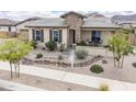 Inviting single-level home with desert landscaping and stone facade, complemented by a cozy front porch at 20961 E Stacey Rd, Queen Creek, AZ 85142