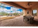 Covered patio with a ceiling fan and a stone table, overlooks a water feature at 7013 E Summit Trail Cir, Mesa, AZ 85207