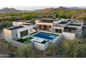 Stunning aerial view of a modern home featuring a sleek pool, spa, and inviting outdoor spaces amidst a lush desert landscape at 7498 E Whisper Rock Trl, Scottsdale, AZ 85266
