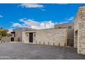 Beautiful exterior stone wall with a paver driveway in a stunning architectural design at 7498 E Whisper Rock Trl, Scottsdale, AZ 85266