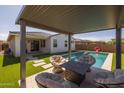Relaxing backyard features covered patio, pool, artificial grass, and outdoor seating area at 9718 E Radioactive Dr, Mesa, AZ 85212