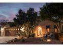 Exterior shot of a well-lit home at twilight with desert landscaping and a stone facade at 12572 W Jasmine Trl, Peoria, AZ 85383