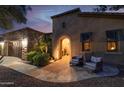 Evening view of a front entrance, with an arched doorway and stone walkway leading to a sitting area at 12572 W Jasmine Trl, Peoria, AZ 85383