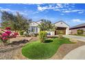 Landscaped front yard with vibrant desert plants, rock features, and artificial turf creating a welcoming curb appeal at 16987 W Princeton Ave, Goodyear, AZ 85395