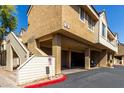 View of tan stucco building with covered parking, stairs, and drought-resistant landscaping under a sunny blue sky at 2035 S Elm St # 218, Tempe, AZ 85282