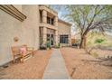 A walkway leads to the front door of this desert home, with a bench and xeriscape landscaping at 26815 N 65Th Ave, Phoenix, AZ 85083