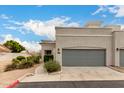 Charming single story home featuring a gray garage door, stone landscaping, and a sidewalk at 295 N Rural Rd # 151, Chandler, AZ 85226