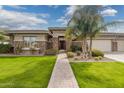 Inviting front yard with brick pathway leading to a stone accented home with mature landscaping and a three-car garage at 3425 E Birchwood Pl, Chandler, AZ 85249