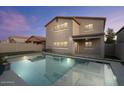 Backyard view of a refreshing pool and covered patio at dusk at 366 E Mule Train Trl, San Tan Valley, AZ 85143